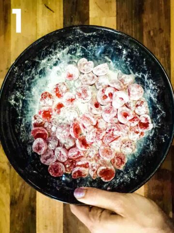 person tossing glace cherries in flour in black bowl to prevent them sinking in cake while baking
