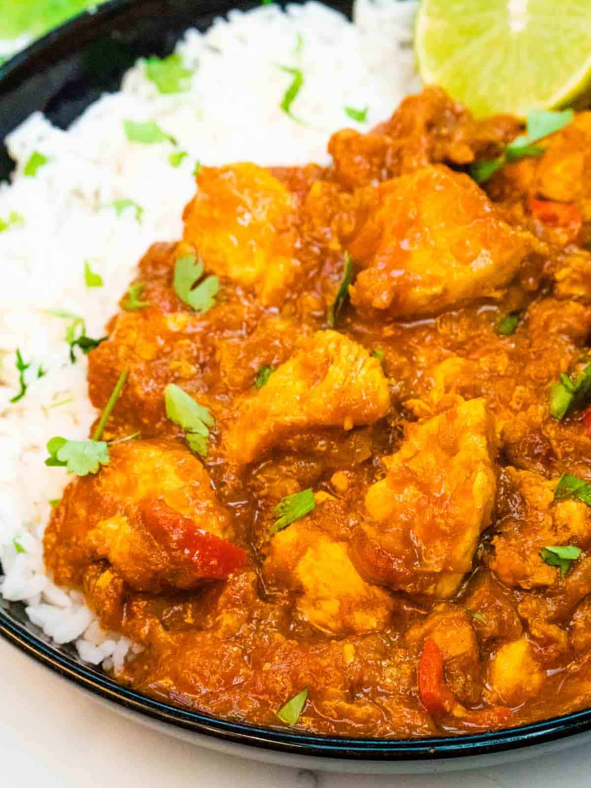 close up of chunks of chicken in a sweet and sour Indian curry sauce