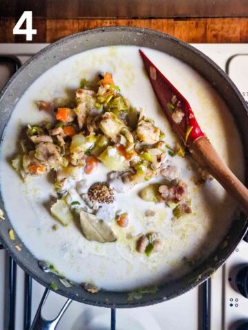 person thickening a chicken soupy stock with cooked flour, bay leaf and single cream in large pan
