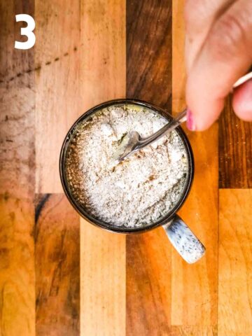 person mixing dry ingredients (oat flour, baking powder and sweetener) in a cup with wet ingredients