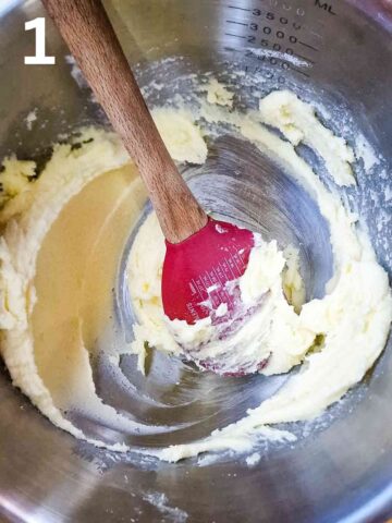 person creaming butterand caster sugar together in a large stainless steel mixing bowl using a wooden spoon