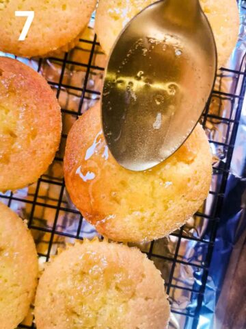 person spooning over a lemon glaze onto pricked lemon cupcakes