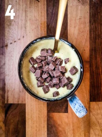 person stirring in chocolate chips in a oat flour mug cake