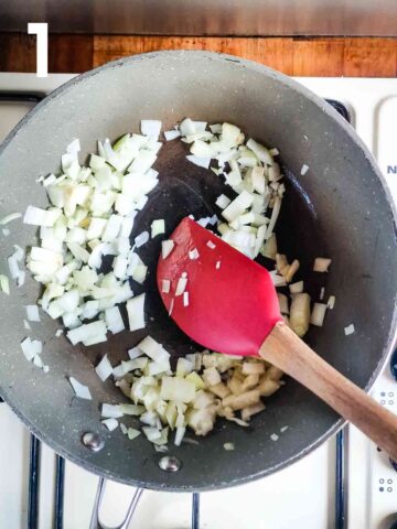 person frying onions and garlic in large frying pan