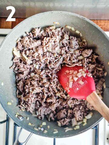 person frying minced beef in large frying pan