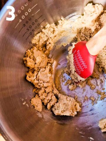 person creaming butter and sugar in a stainless steel mixing bowl