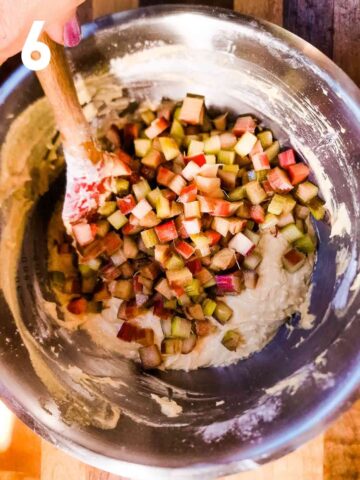 person folding in drained diced rhubarb into cake batter