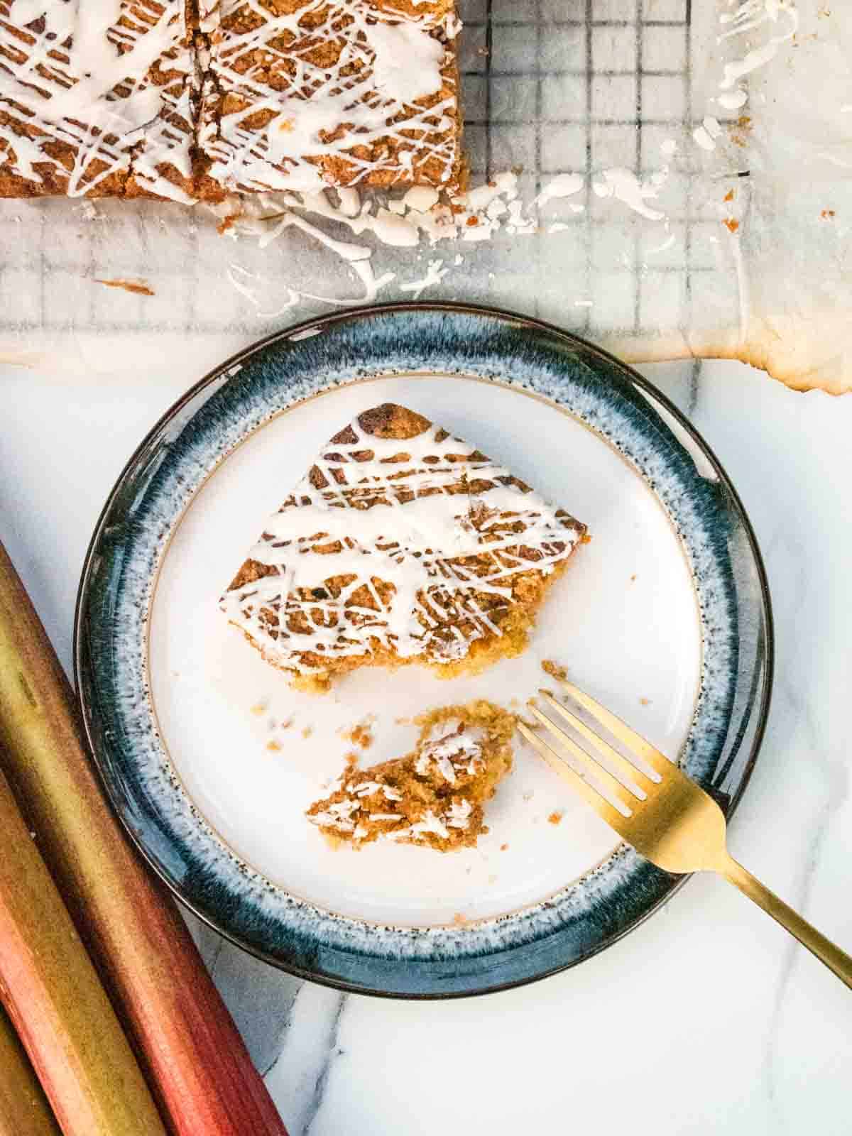 person cutting rhubarb coffee crumble cake with a gold fork on white plate