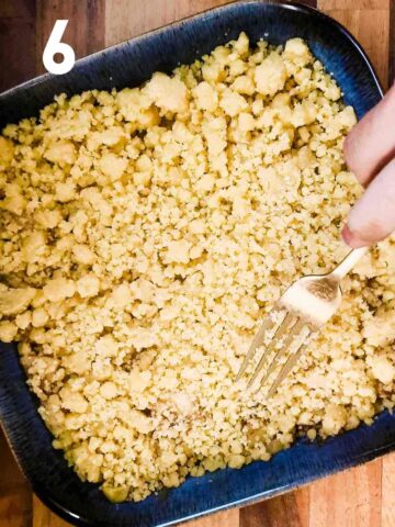person spreading crumble mixture over fruit before baking in oven