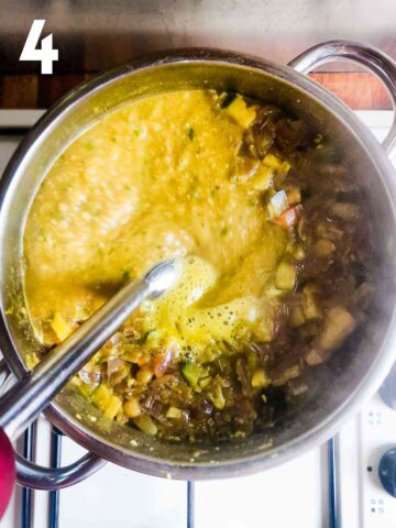 person blending carrot courgette vegetable soup in a pan with stick blender