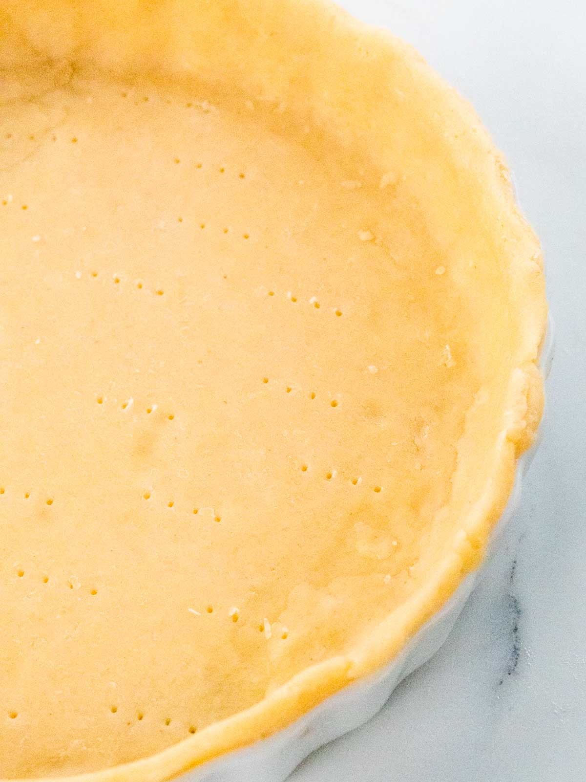 close up of cheddar cheese shortcrust pastry in a ceramic quiche dish