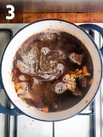 beef stock, oats, red wine with beef carrots and onions in a Denby casserole dish on hob