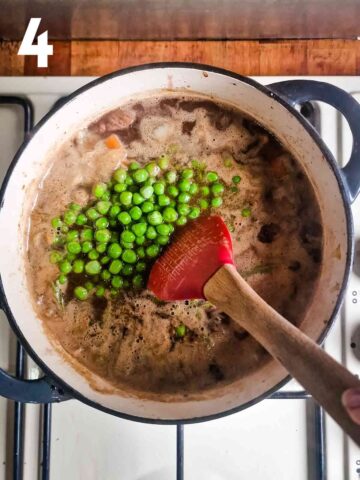 person stirring in fresh garden peas and rosemary in an easy beef hotpot