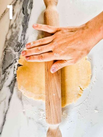 person rolling homemade savory quiche crust with a wooden rolling pin on a floured kitchen worktop
