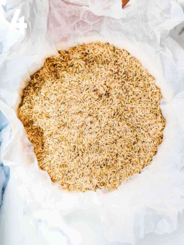 quiche dish lined with scrunched up baking paper full with dried brown rice as baking beads