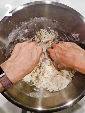 person rubbing butter, flour and cheese together with fingertips to make pastry breadcrumbs