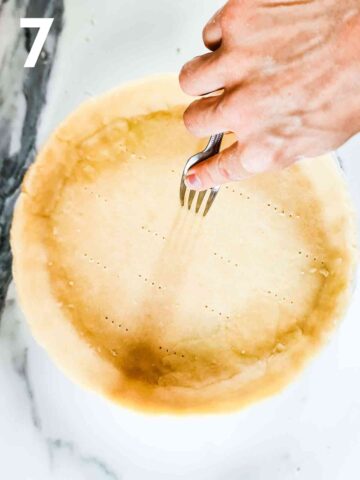 person pricking quiche pastry with a fork