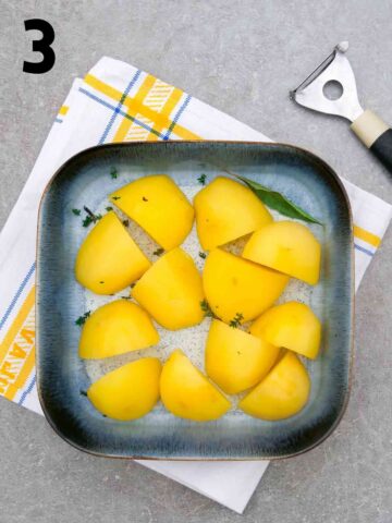 square baking dish with par boiled potatoes and fresh herbs