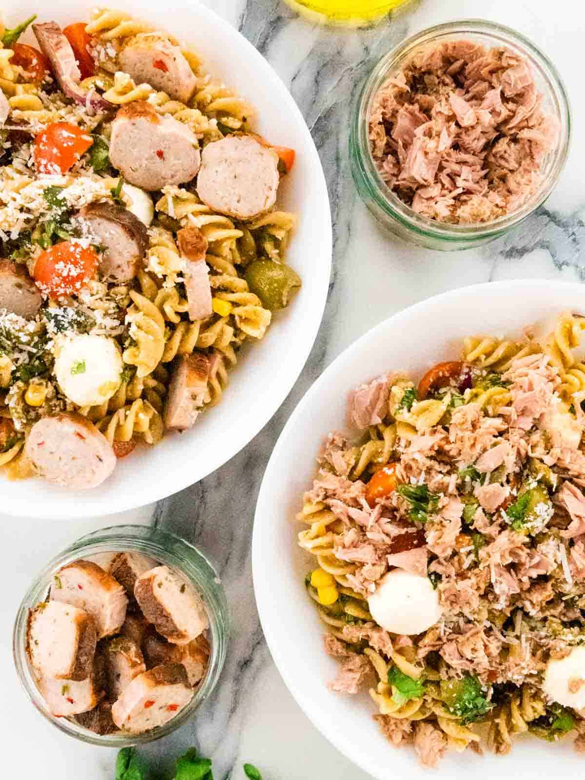 close up of cooked sliced sausage pasta freddo in one bowl and cold pasta with tuna in the other