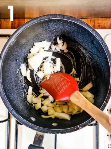 person sauteing onions and garlic in cooking oil spray in large saucepan