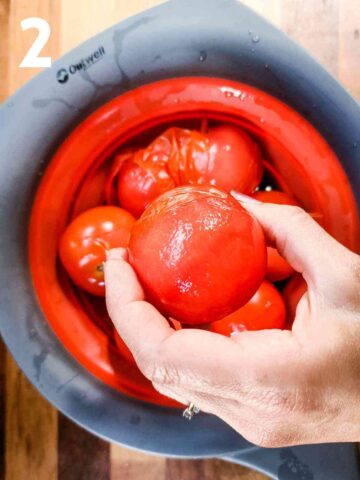 person peeling tomato skins off after leaving in boiling wate and running under a cold tap in a colander
