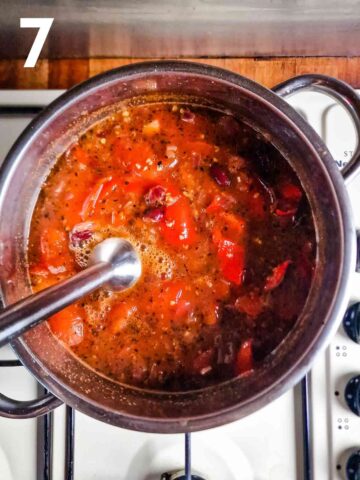person blending roasted tomato pepper soup with a stick blender