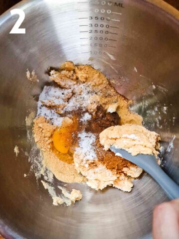 breadcrumbs, soft cream cheese, herbs, spices, egg and seasoning being mixed in a large stainless steel mixing bowl
