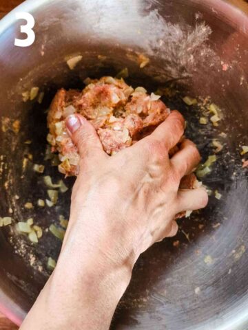 person squishing ground beef and cooked onions with breadcrumbs, herbs and spices into a large ball of meat
