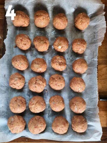 24 golf ball sized meatballs on a lined baking tray