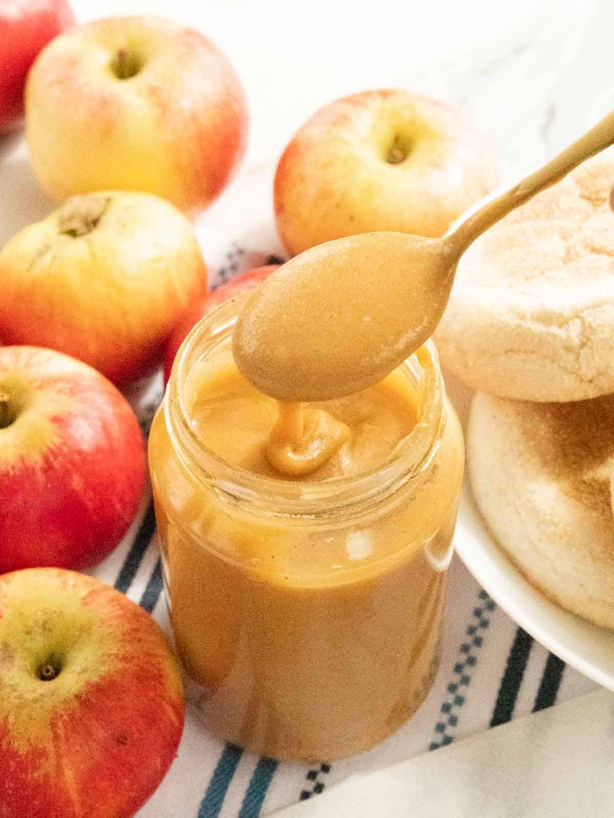 spoon of apple curd drizzling into the jar while spooning out to eat with toasted English muffins