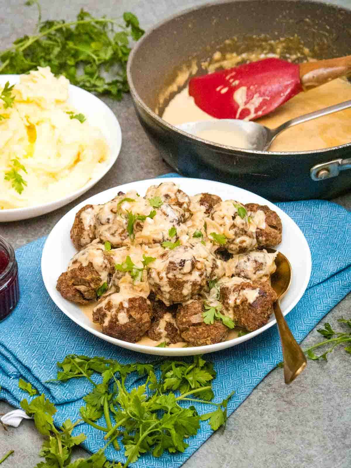creamy meatball gravy poured on top of beef meatballs and garnish of fresh parsley on blue tea towel
