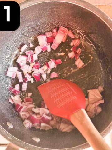 person frying diced red onions in large soup pan