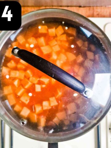 saucepan covered full of tomato, stock, veggies, chicken and chorizo simmering until cooked