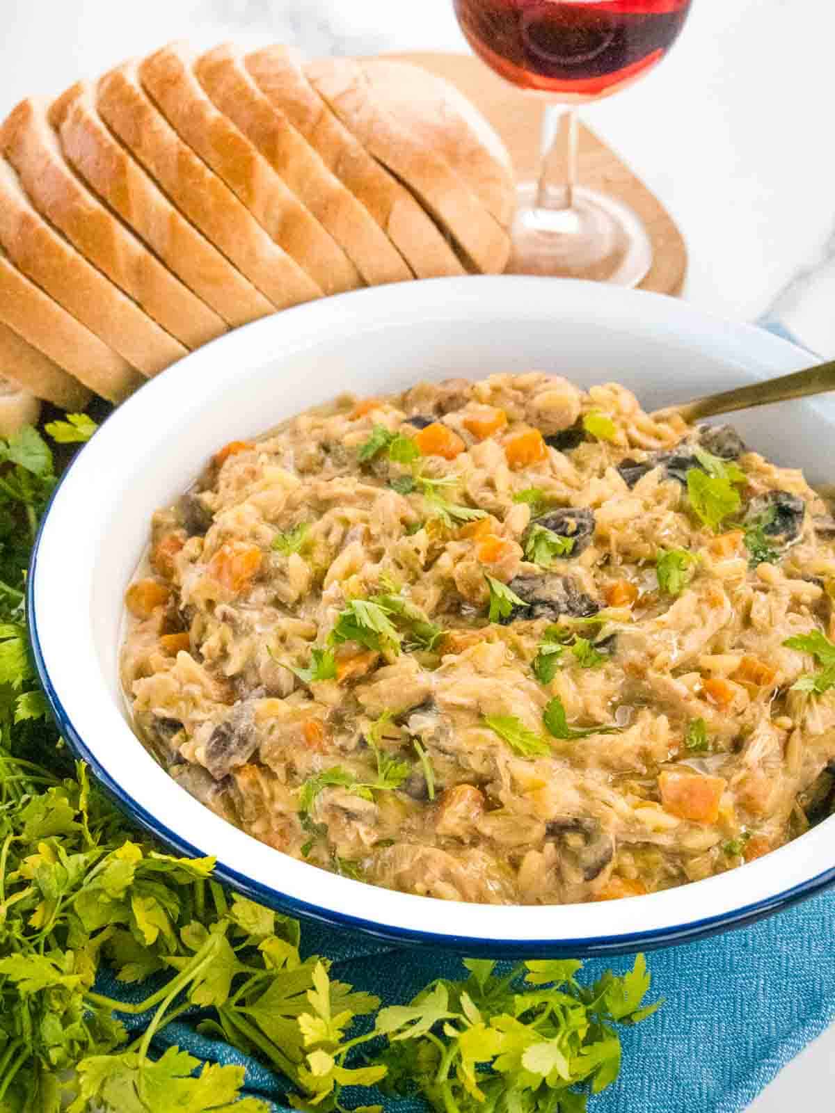 orzo chicken served with pinot grigio wine and bread on white marble kitchen worktop