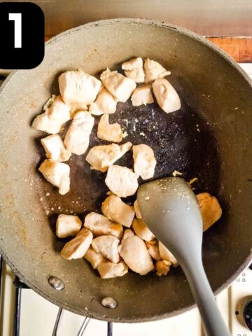 person browning diced chicken breast in large frying pan