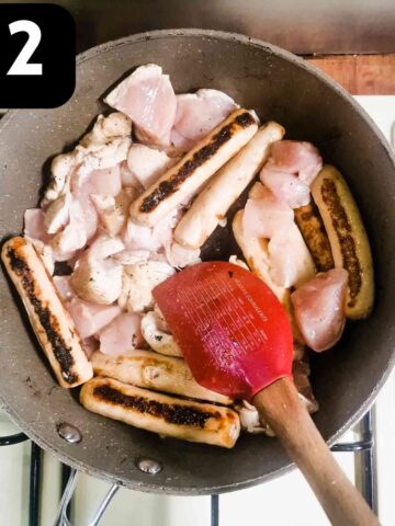 person frying diced chicken with sausages in frying pan