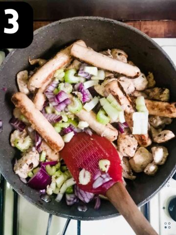 person frying mixed vegetables with chicken and sausages