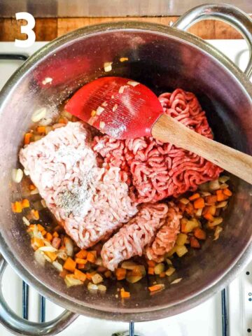 ground beef and pork added to a large pan before cooking for a meaty ragu