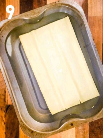 person cooking fresh lasagne sheets in a large deep tray with boiling water