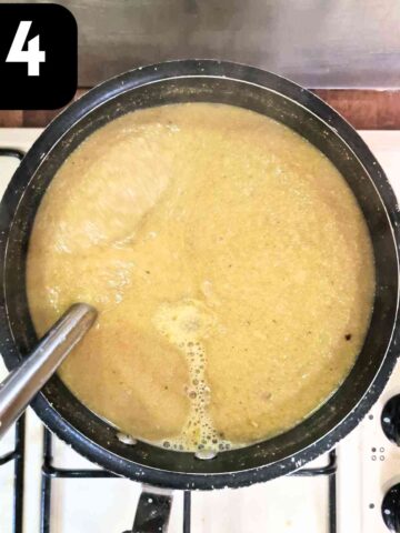 person blending cauliflower soup with shand blender in pan