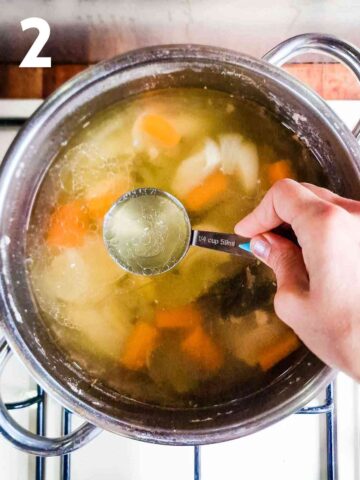 person scooping out broth from the cooking pot that had pork in it to use in the vitel toné sauce
