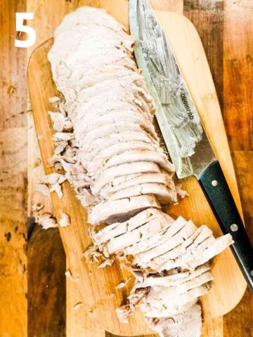 sliced tenderloin pork with fat removed on a wooden chopping board with sharp knife