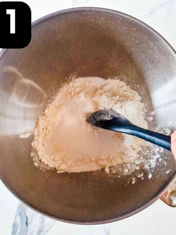 persin mixing dry cookie ingredients together in kitchenaid mixing bowl jug