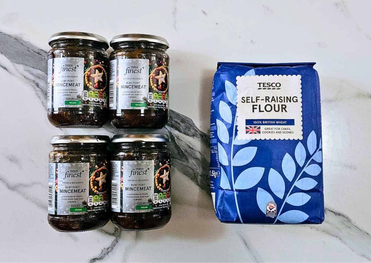 Four jars of Tesco Finest ruby port mincemeat beside a bag of self-raising flour.